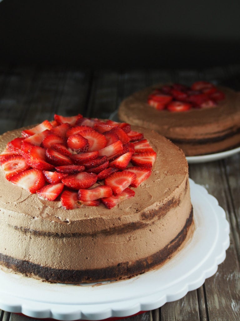 Chocolate cake frosted with cocoa whipped cream, and adorned with fresh strawberries on top.