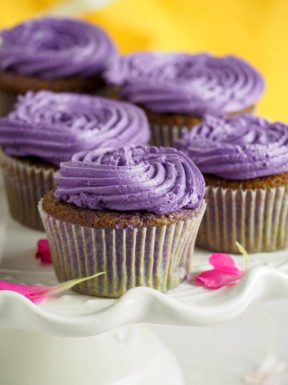 Ube cupcakes with ube swiss meringue buttercream on a cake stand.