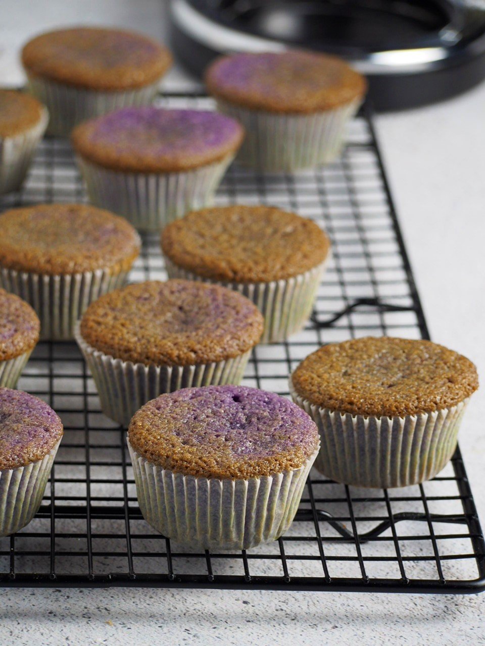 Ube cupcakes without icing yet, cooling on a wire rack.
