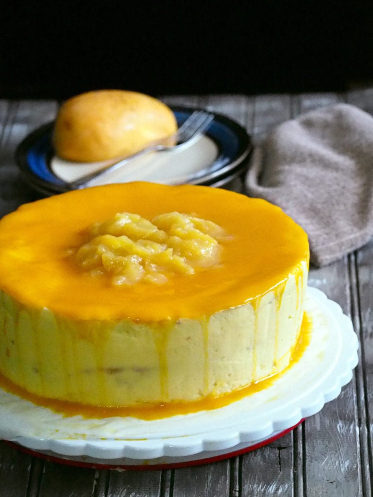 mango chiffon cake is on a cake plate, topped with mango slices.