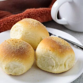 Three pieces of pandesal on a serving plate.