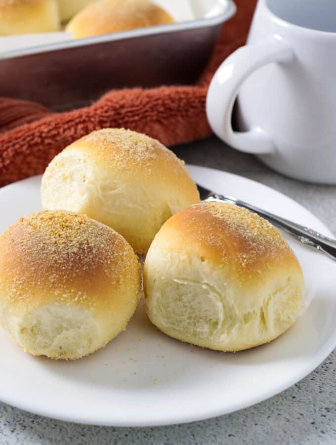 Three pieces of pandesal on a serving plate.