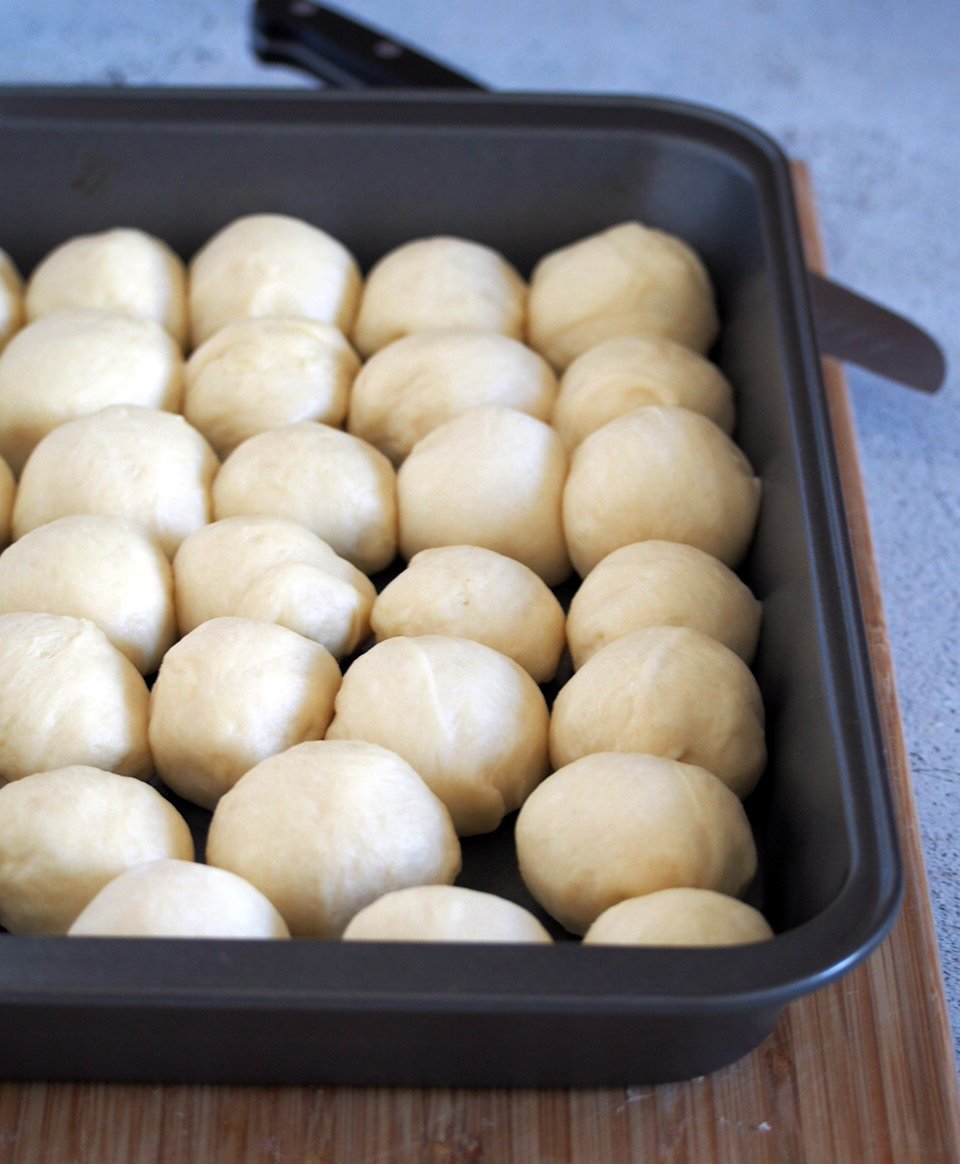The shaped dough of Hawaiian Rolls arranged in a baking pan.