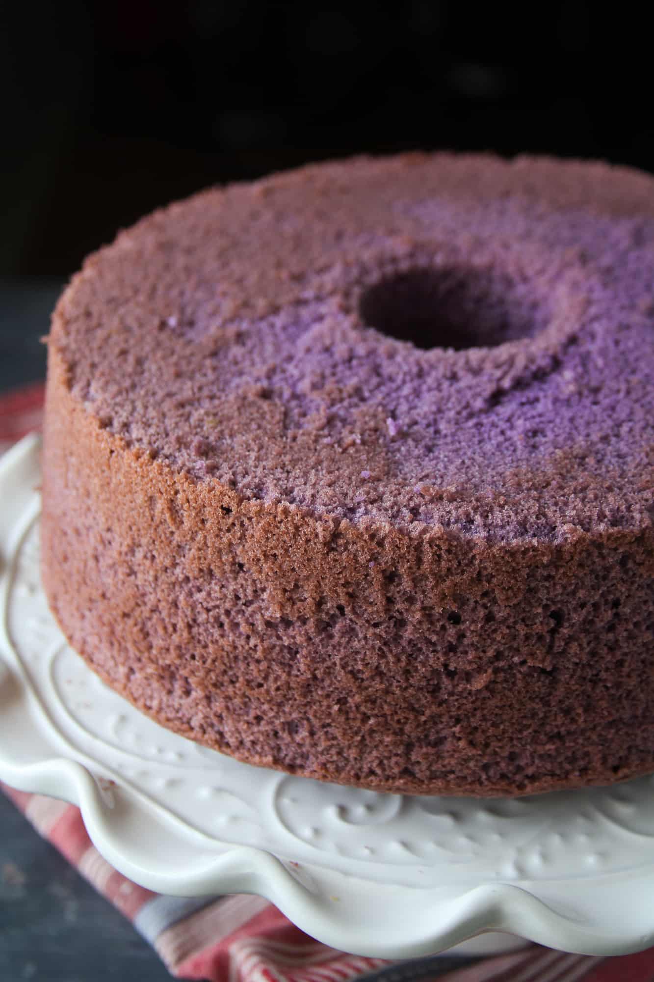 The baked ube chiffon cake without frosting on a cake stand.