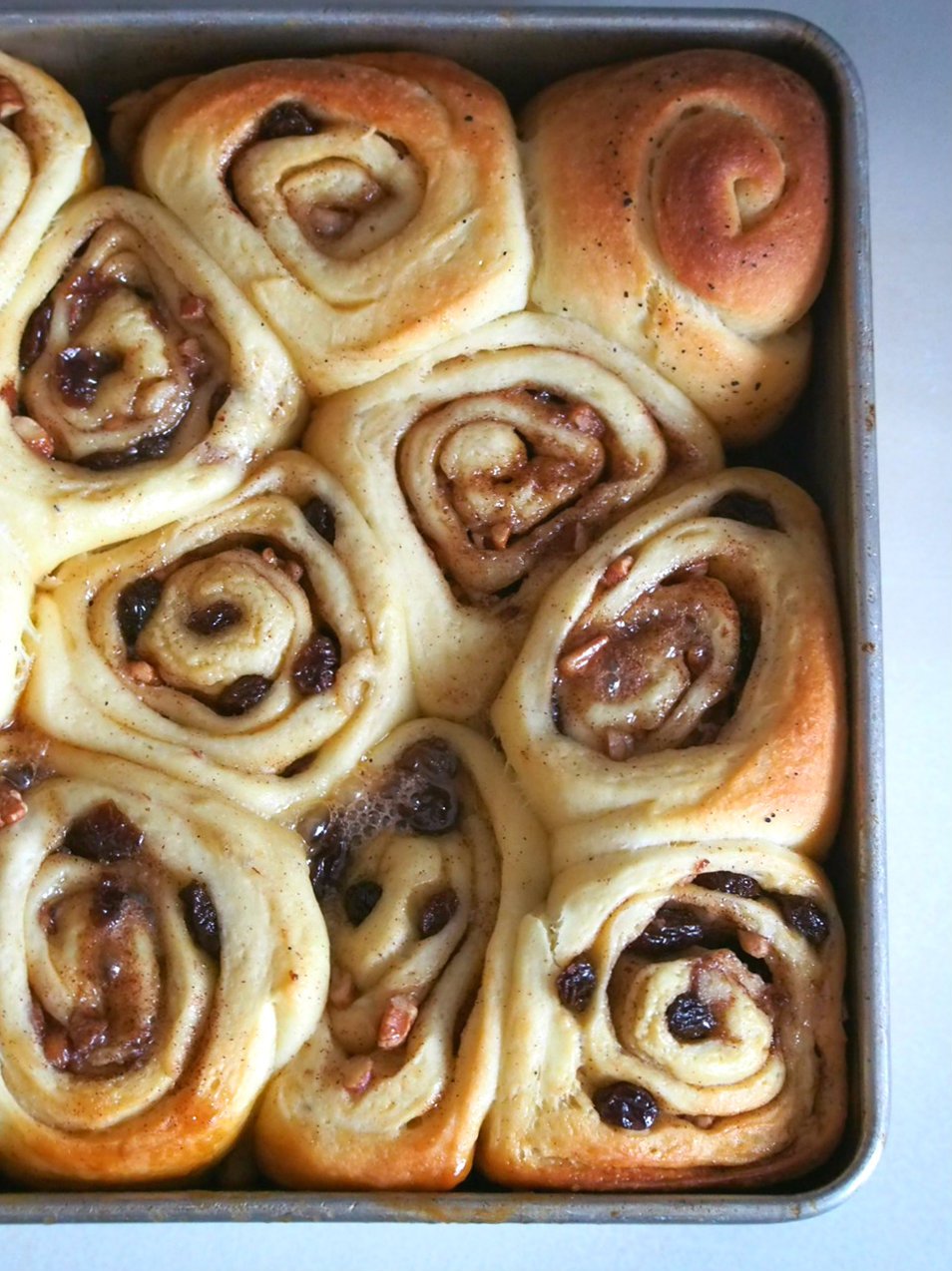 These sticky buns are loaded with pecan nuts and raisins, and covered in a sweet and sticky brown sugar topping. These are the ultimate cinnamon rolls using brioche dough that is packed with  flavorful cinnamon sugar filling.