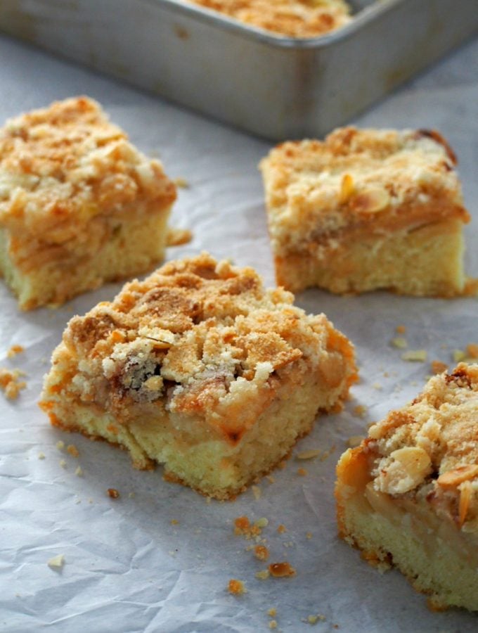 Square slices of Apple Streusel Coffee Cake on a big sheet of parchment paper.