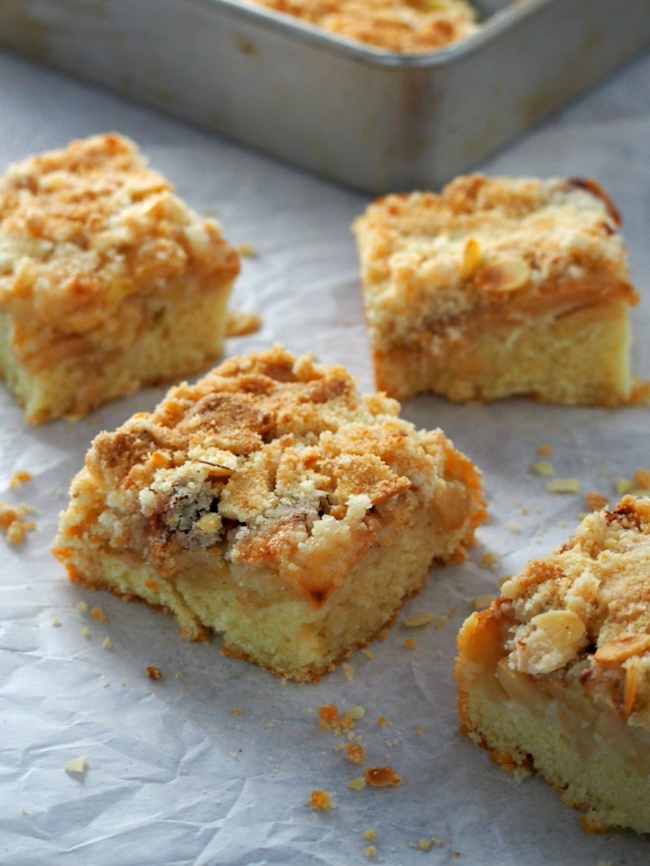Square slices of Apple Streusel Coffee Cake on a big sheet of parchment paper.