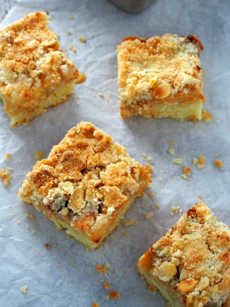 Slices of apple streusel coffee cake laying on a parchment paper, top view.
