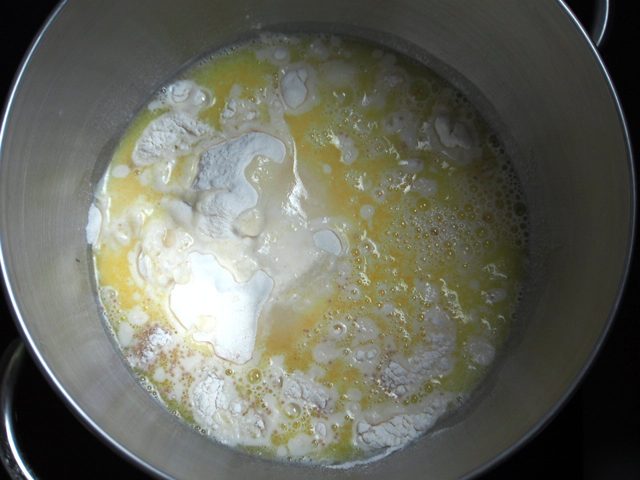 The dough for mini cinnamon rolls are being mixed in a large mixing bowl.