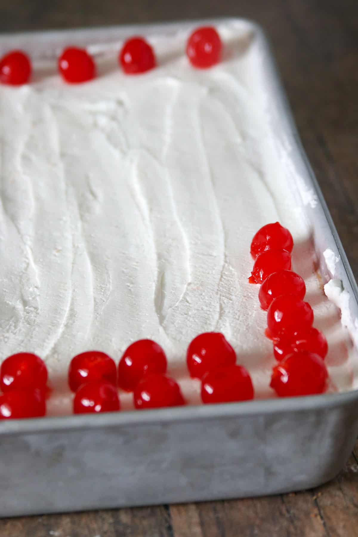 Whole Tres Leches Cake garnished with maraschino cherries.