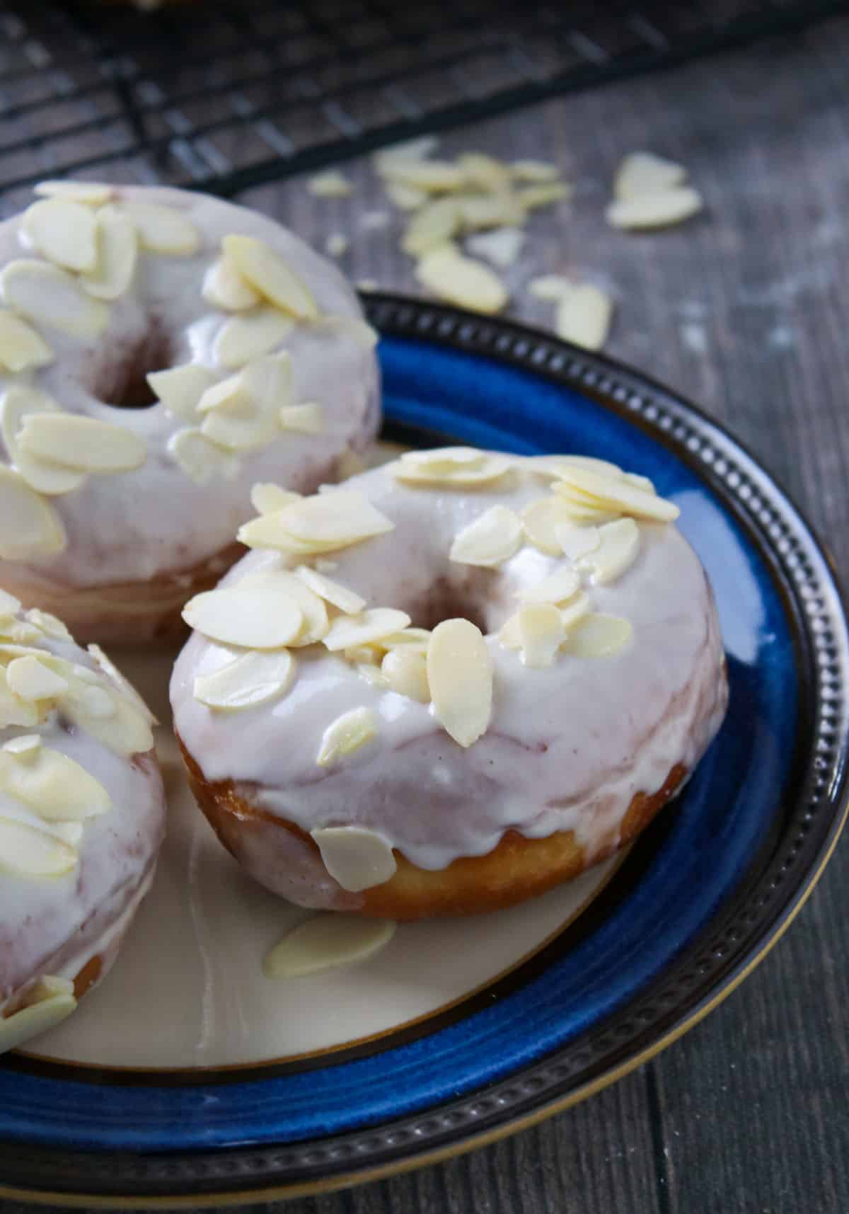 Three white chocolate yeast donuts on a plate.
