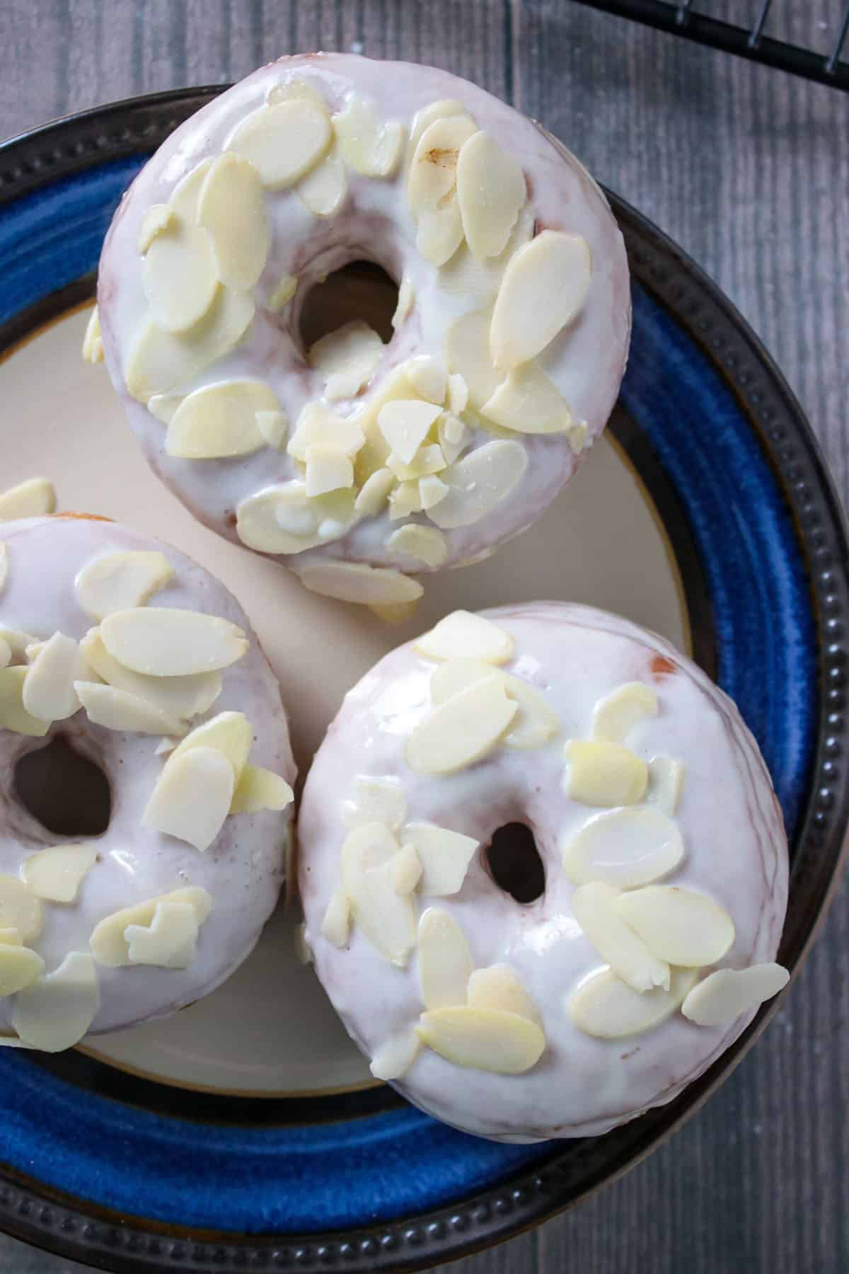 Three yeast donuts with white chocolate gaze on a plate.