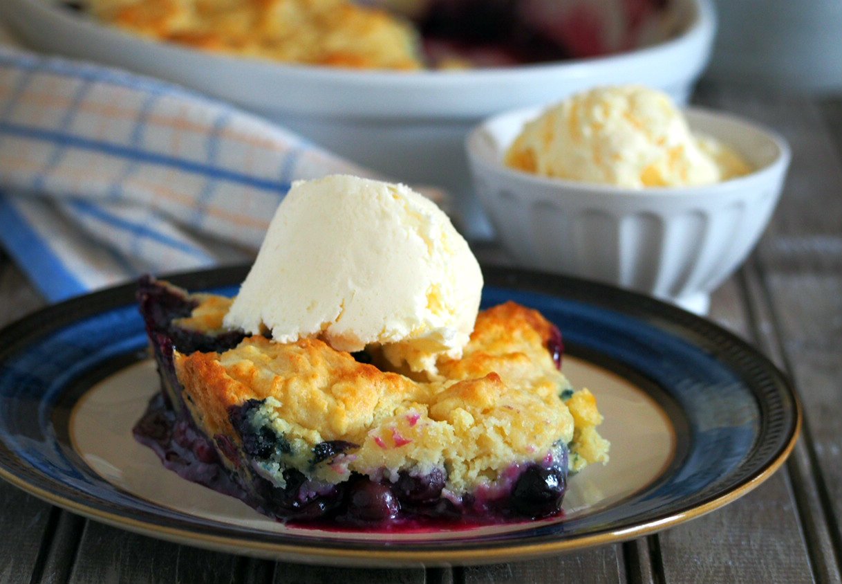 A slice of blueberry cobbler topped with vanilla ice cream.