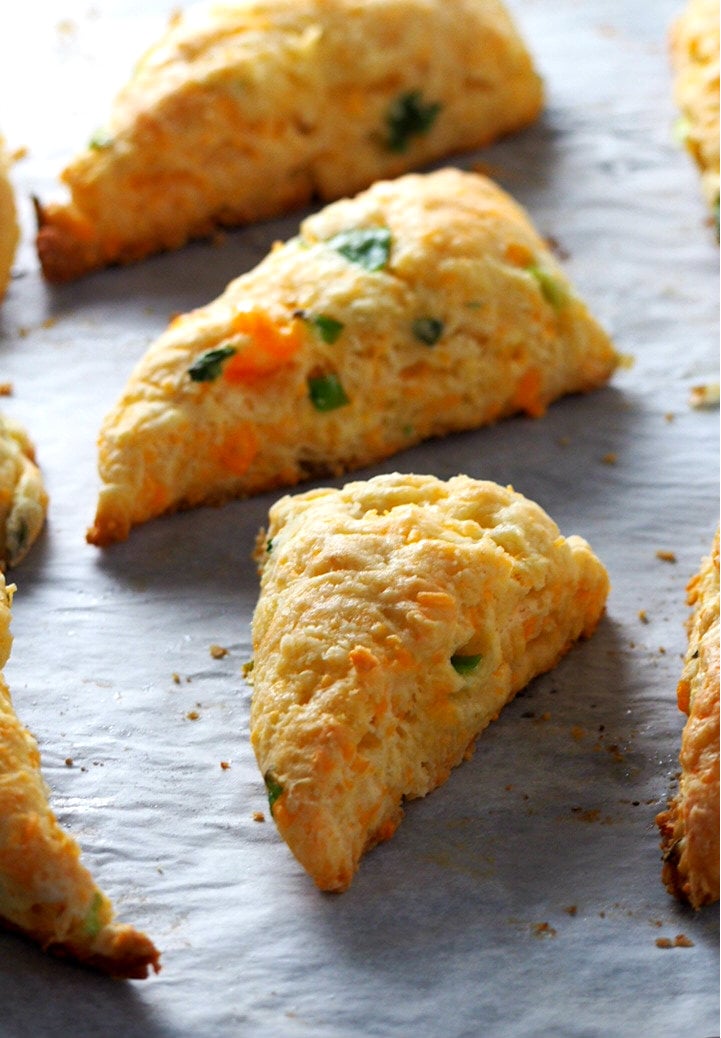 Freshly baked cheese scones with scallions on a baking tray.