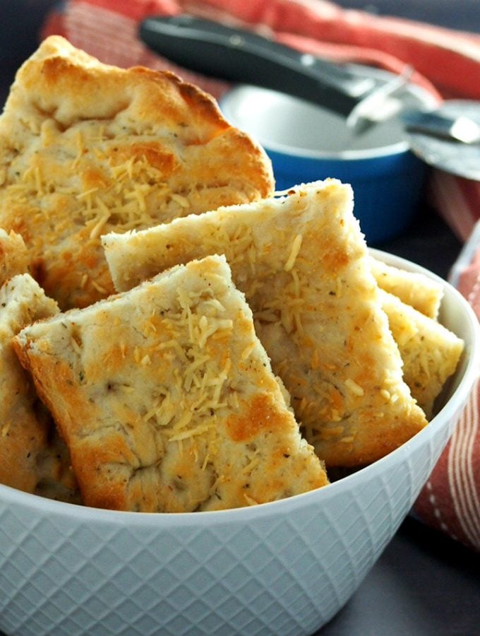 Focaccia bread sliced into rectangles and arranged in a bowl.