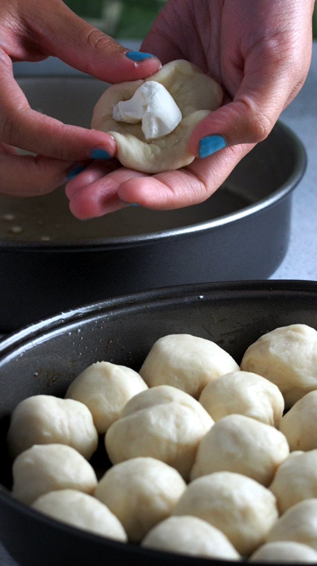 Placing cream cheese in the center of dough portion to make beehive buns.