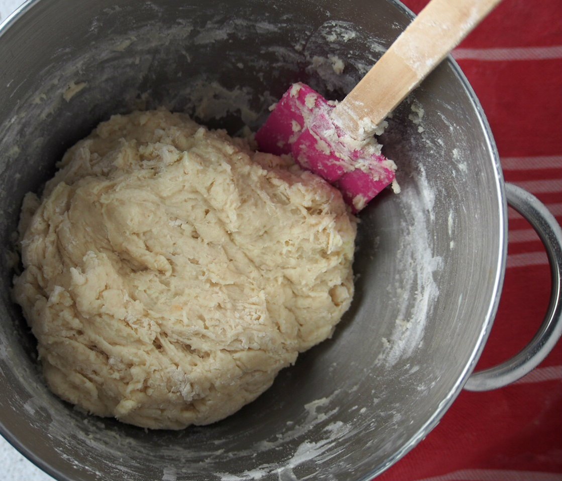 The dough of the beehive buns being stirred into a ball in the center of a bowl.
