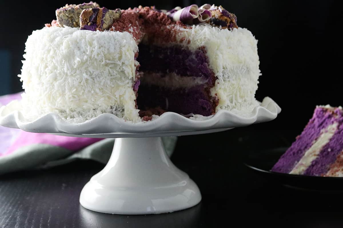 Ube cake with white chocolate coconut cream on a cake stand.