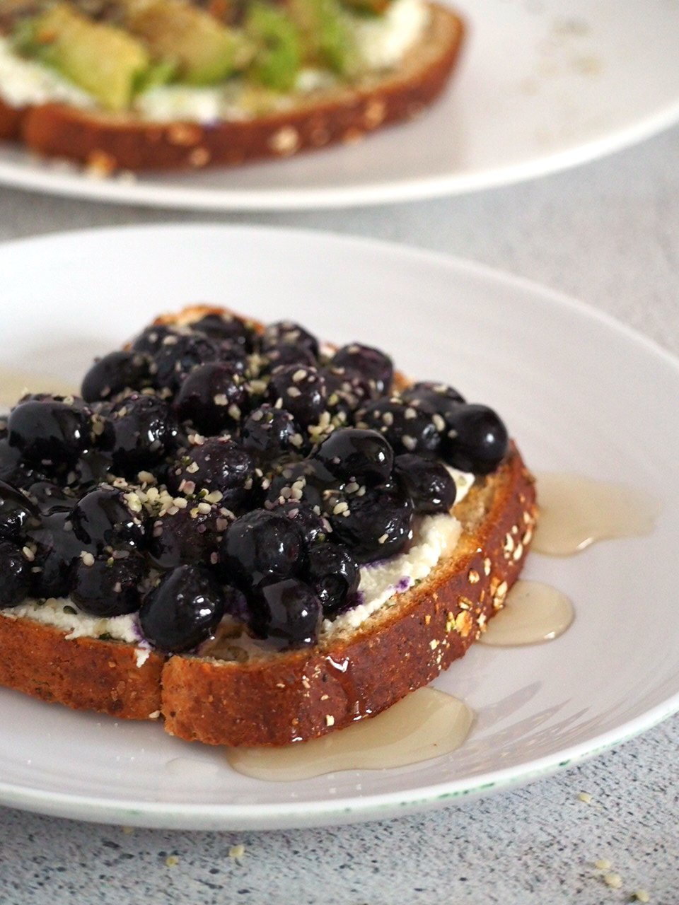 Blueberry breakfast toast on a plate, dripping with honey on the side.