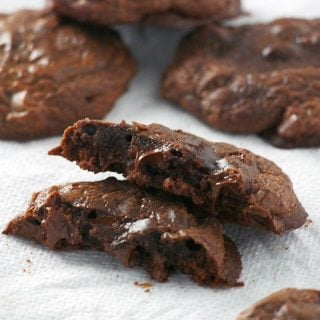 A piece of brownie cookie halved to show the gooey chocolate inside.