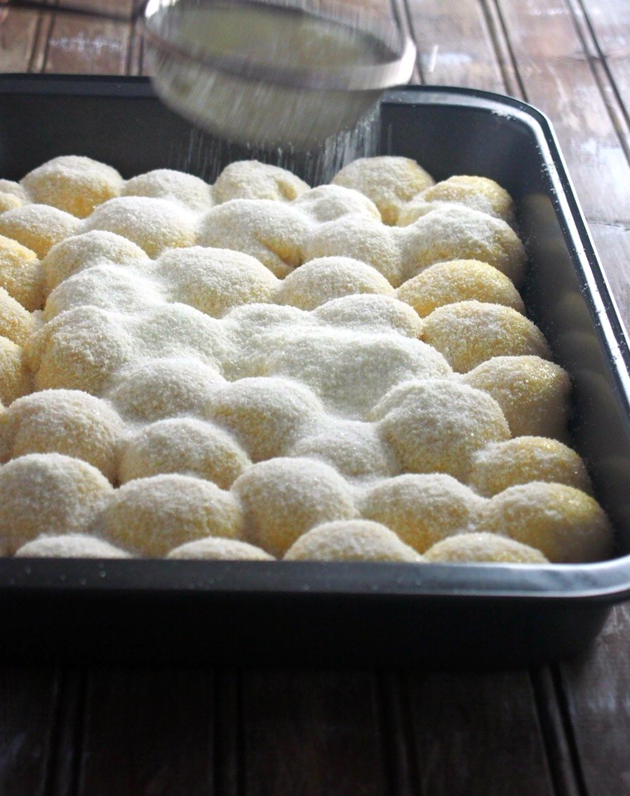 Dusting the unbaked buns with milk powder and sugar mixture.