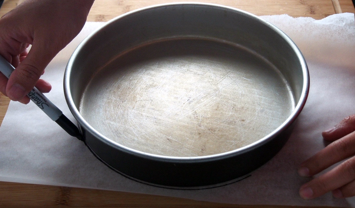 Tracing the round cake pan shape into the parchment paper.