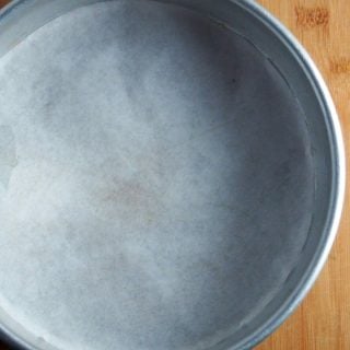A 9-inch cake pan that is lined with parchment paper.