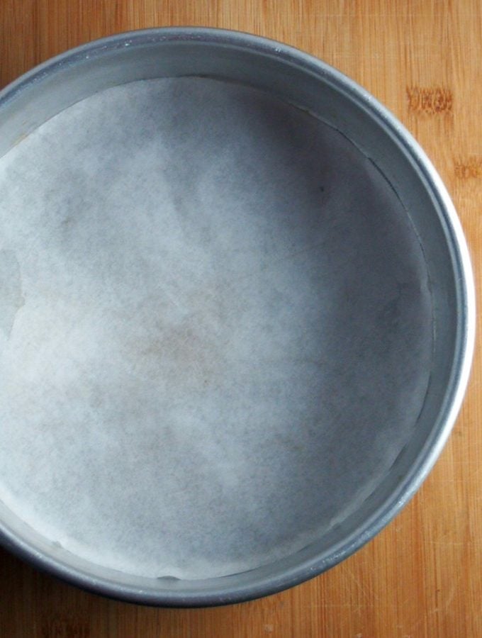 A 9-inch cake pan that is lined with parchment paper.