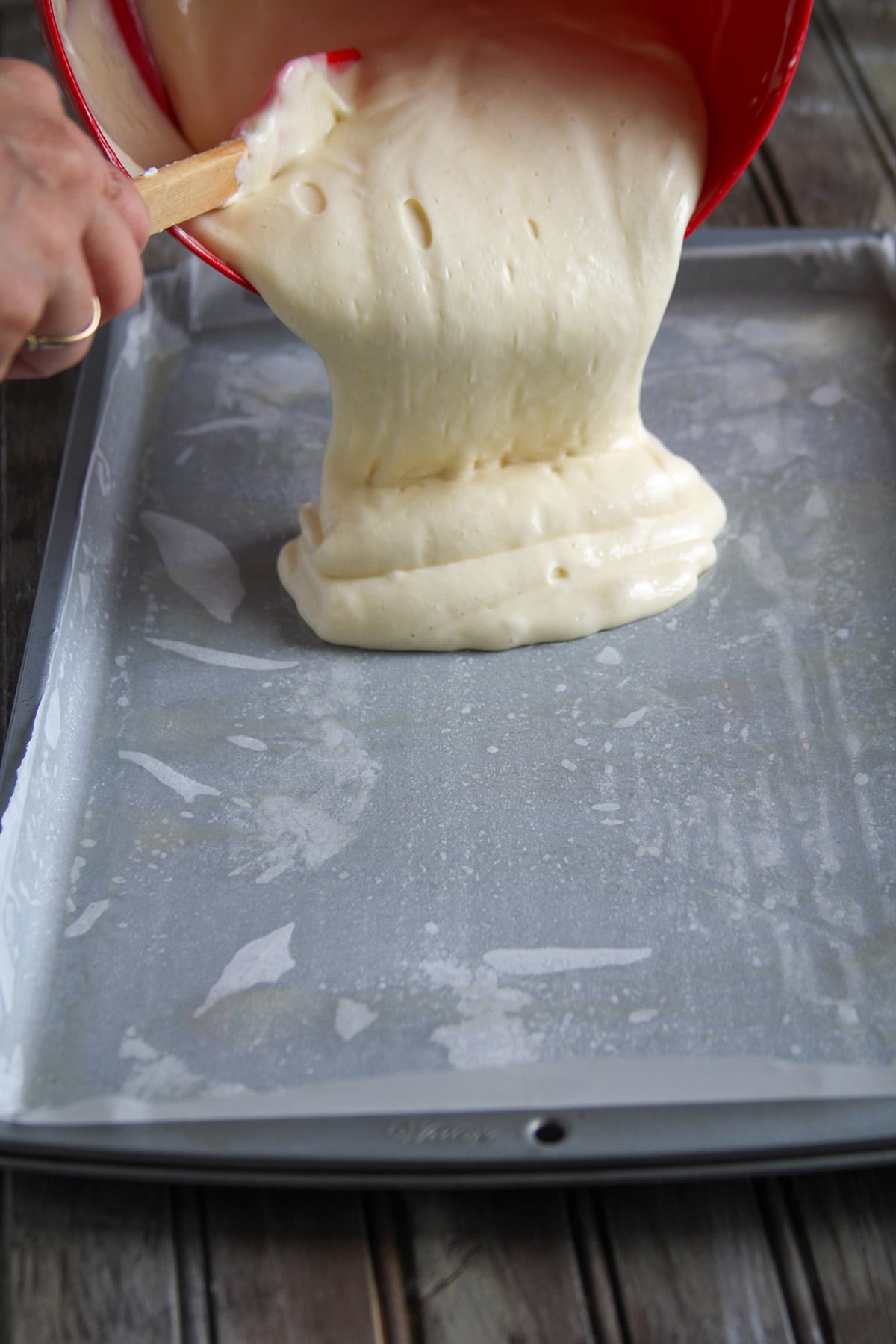 Pouring the vanilla swiss roll batter on the pan.