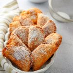 Peach mango pies dusted with powdered sugar, arranged on a serving plate.
