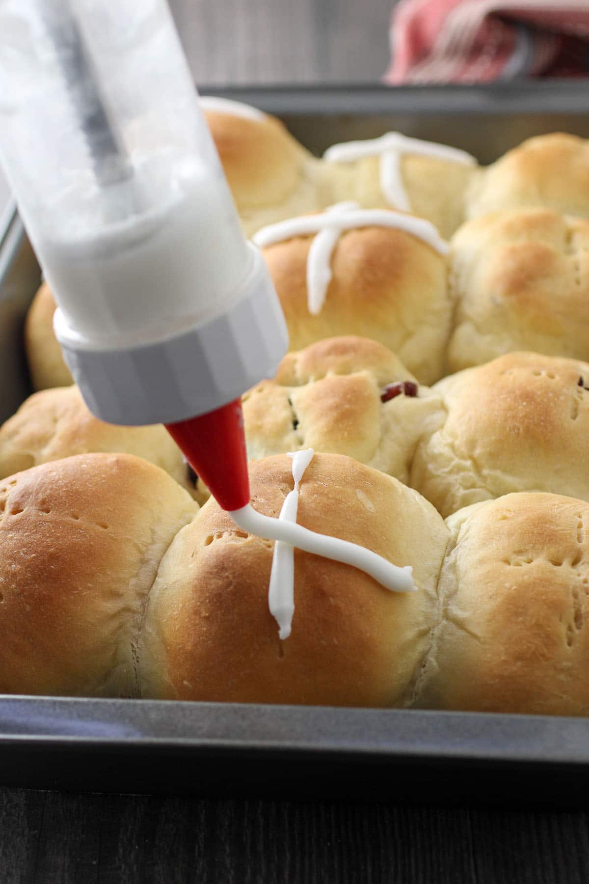Piping the cross icing into the hot cross buns.