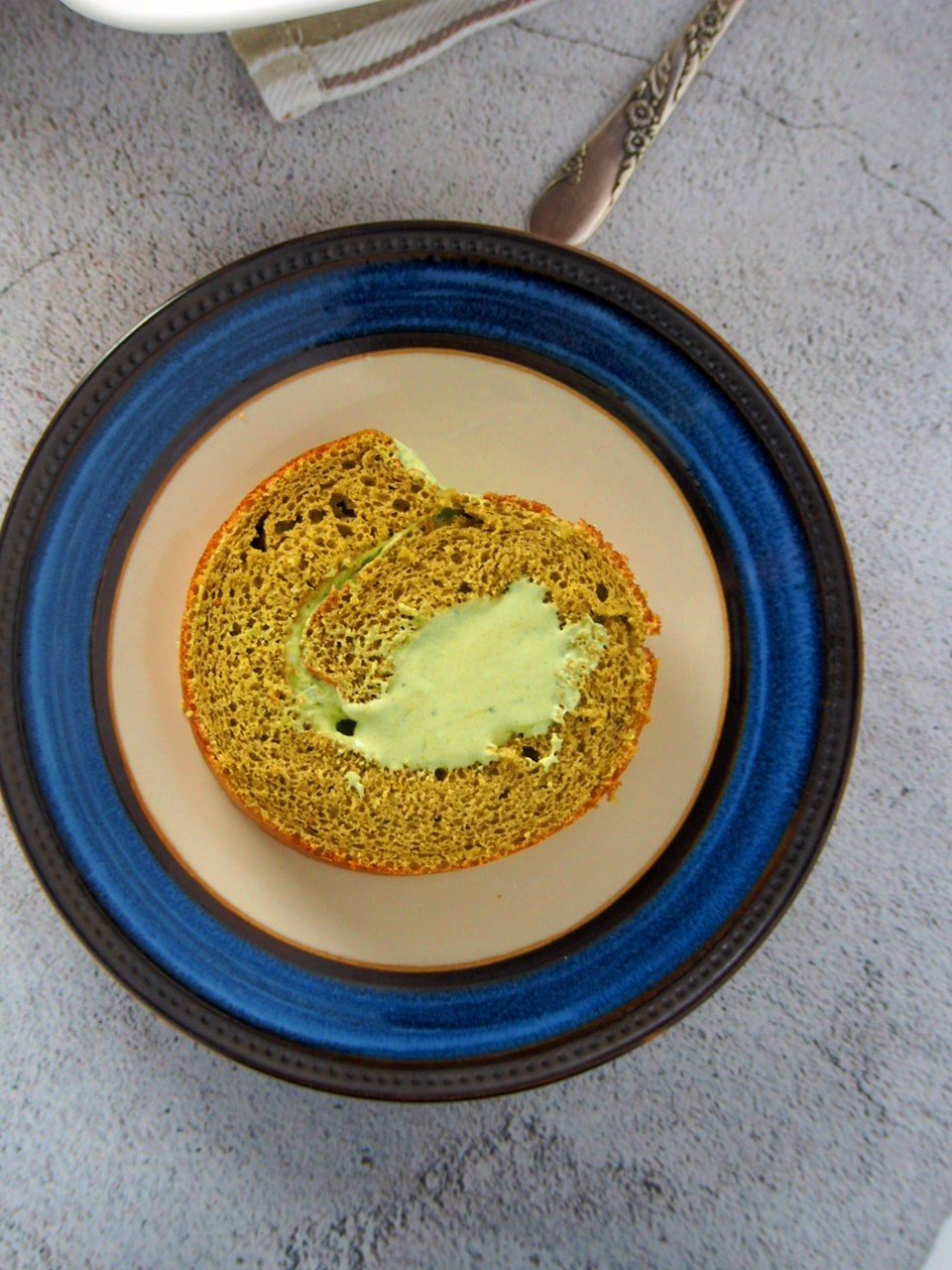 A slice of matcha roll cake on a saucer plate.