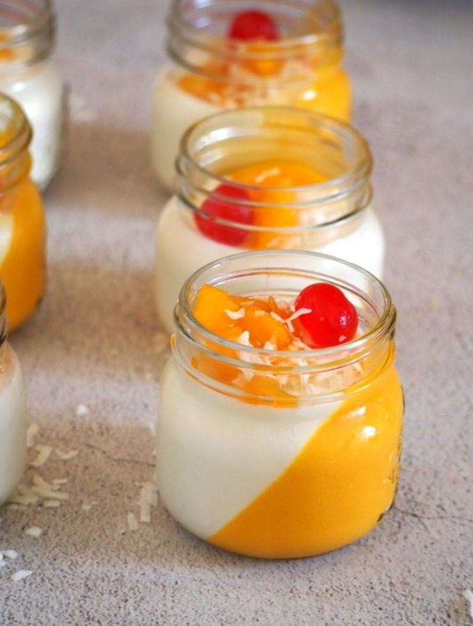Coconut Mango panna cotta in jars, lined up in the table.