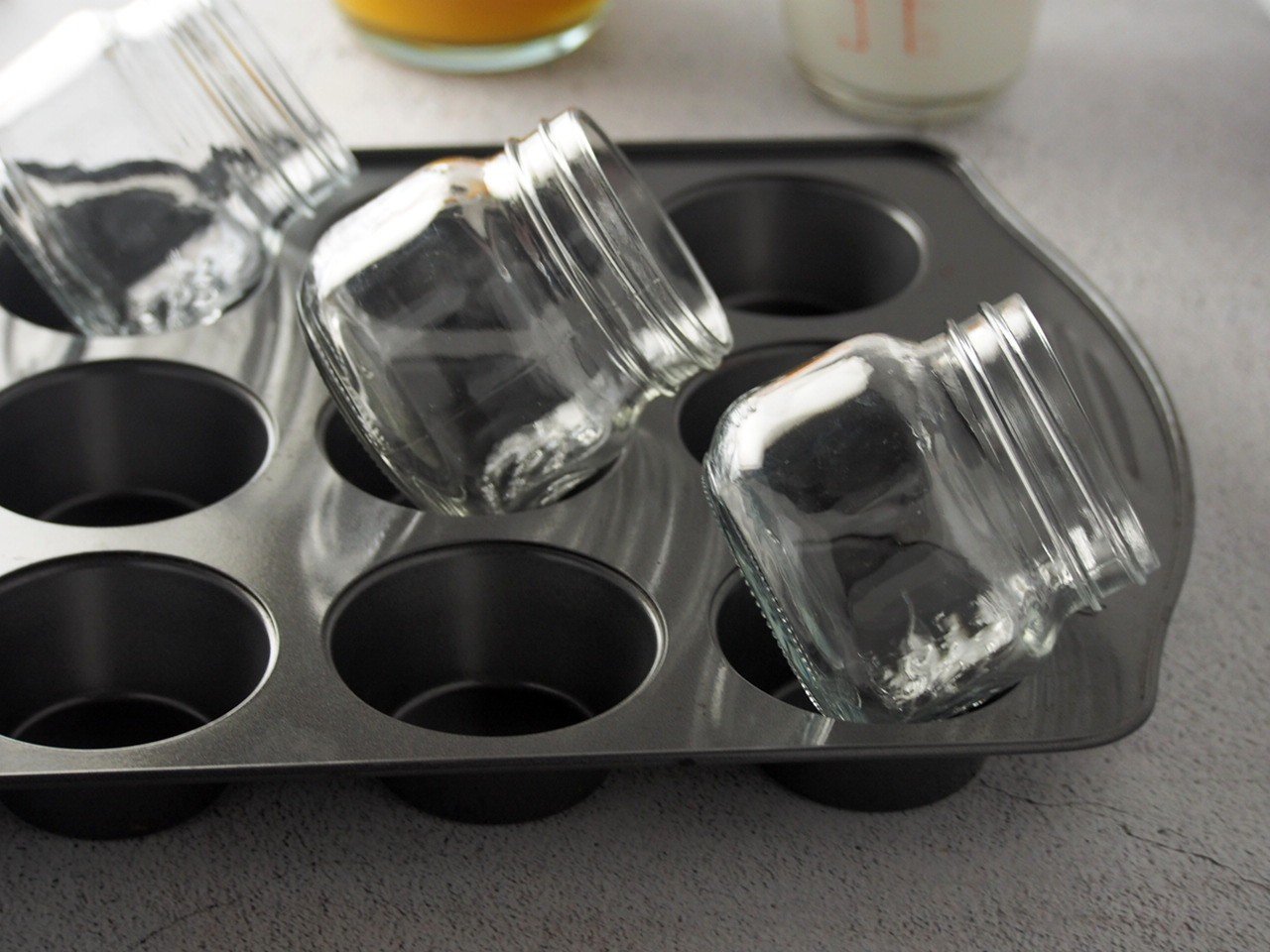 Tilted mason jars in holes of muffin pans.