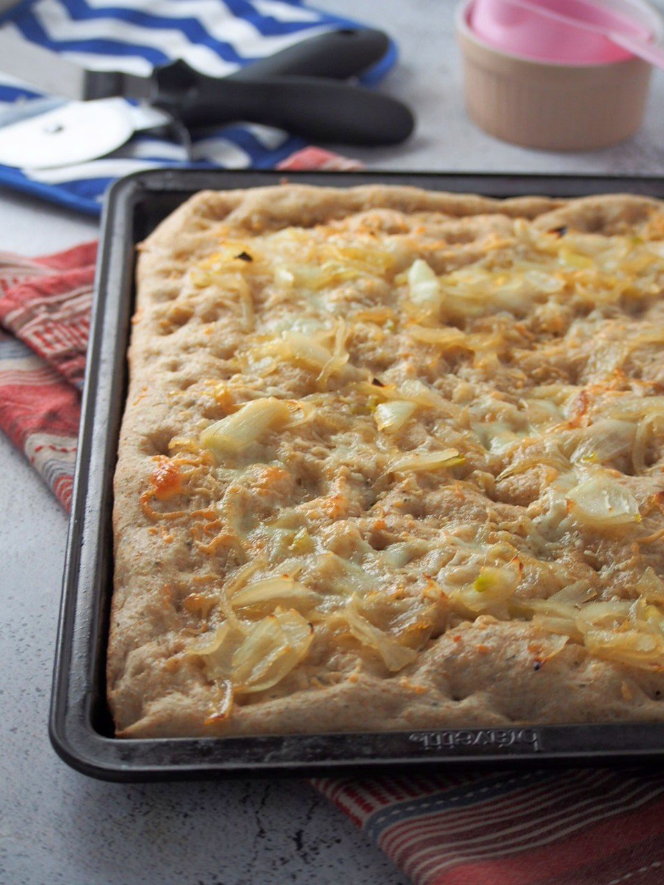 Whole wheat focaccia with caramelized onions in a baking pan.
