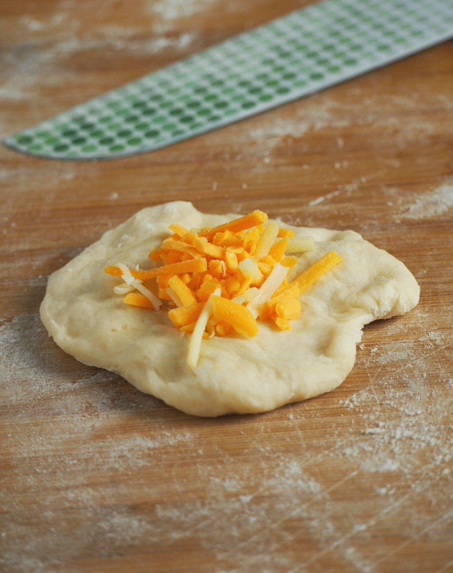 Filling the dough with shredded cheddar cheese.