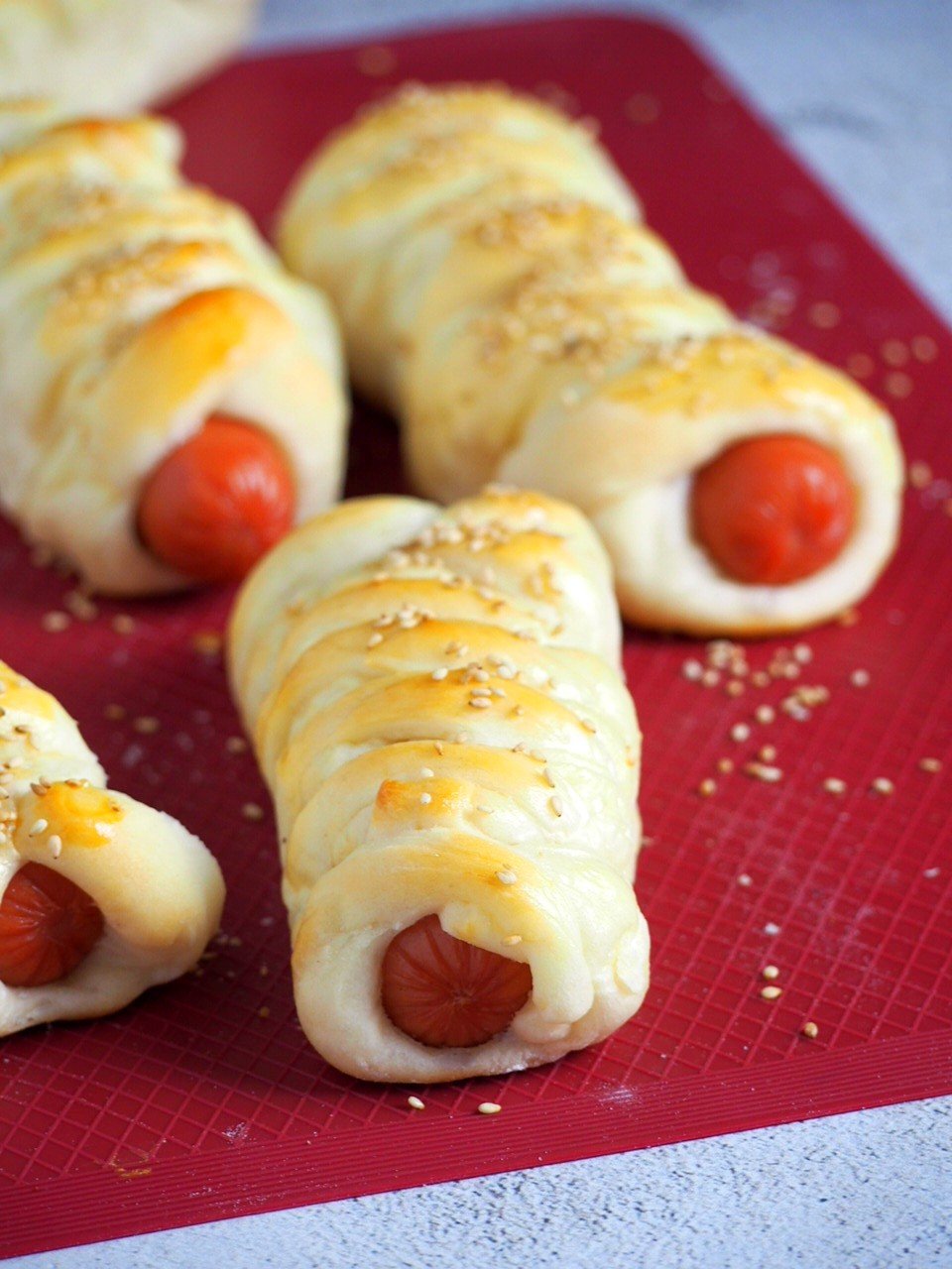 Braided hotdog buns on a red silicone mat.