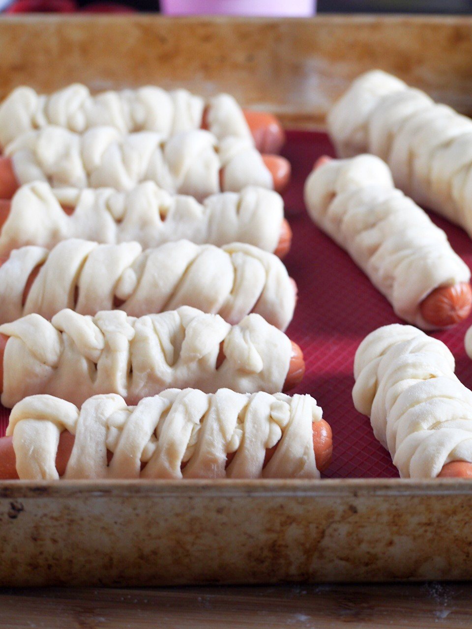 Assembled braided hotdog buns on the baking tray.