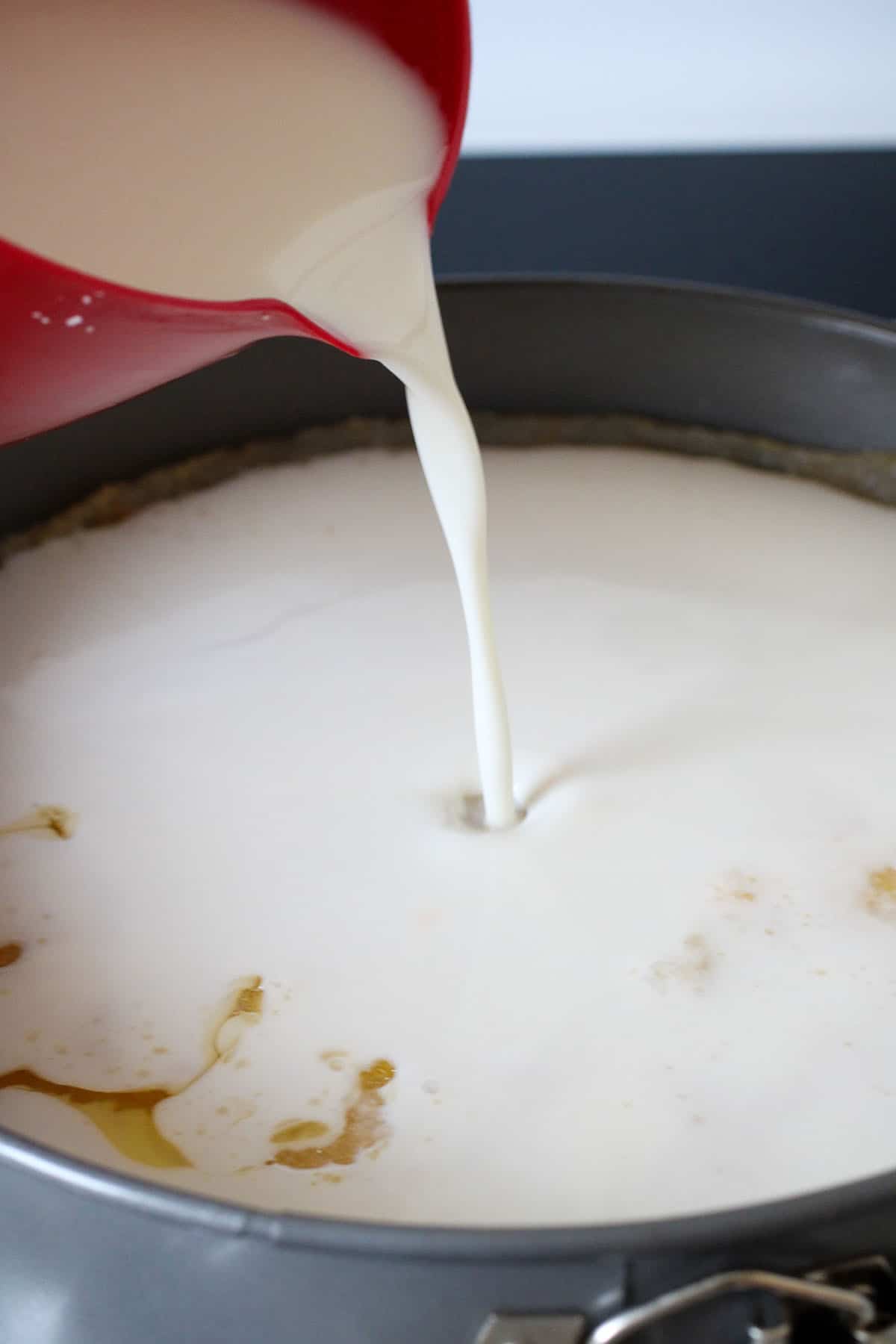 Pouring the milk topping over the cassava base.