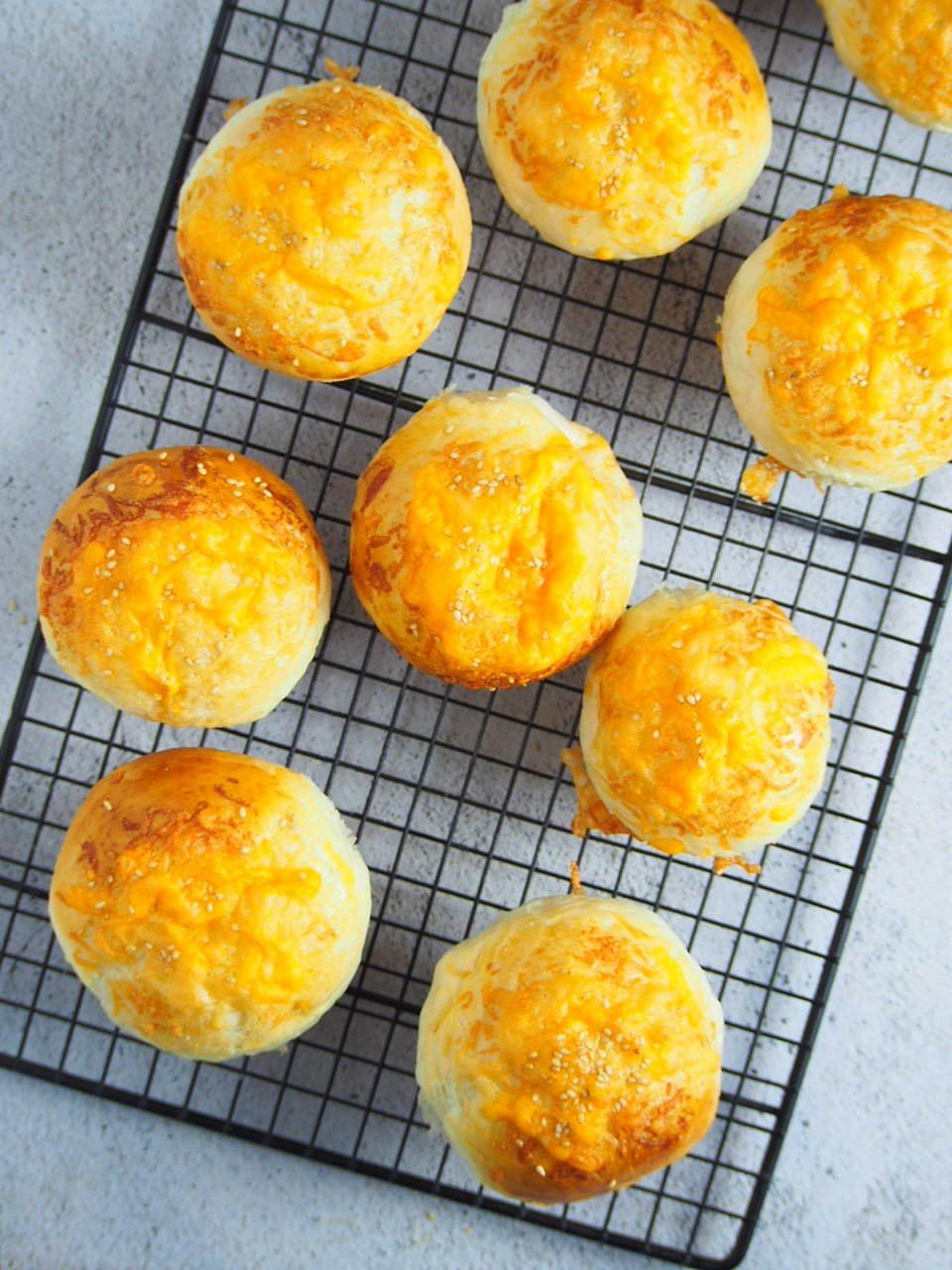 Cheddar cheese buns on a cooling rack.