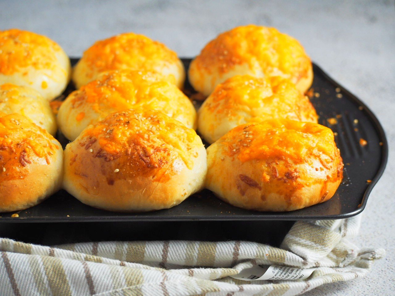 Side angle shot of cheese buns on a muffin pan.