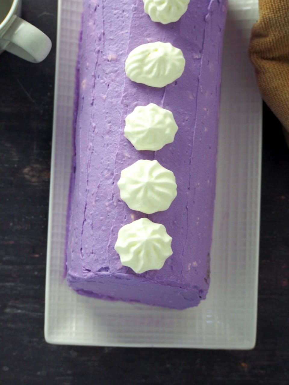 Top angle shot of ube cake roll on a plate.