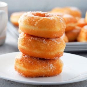 Three donuts stacked on small plate.