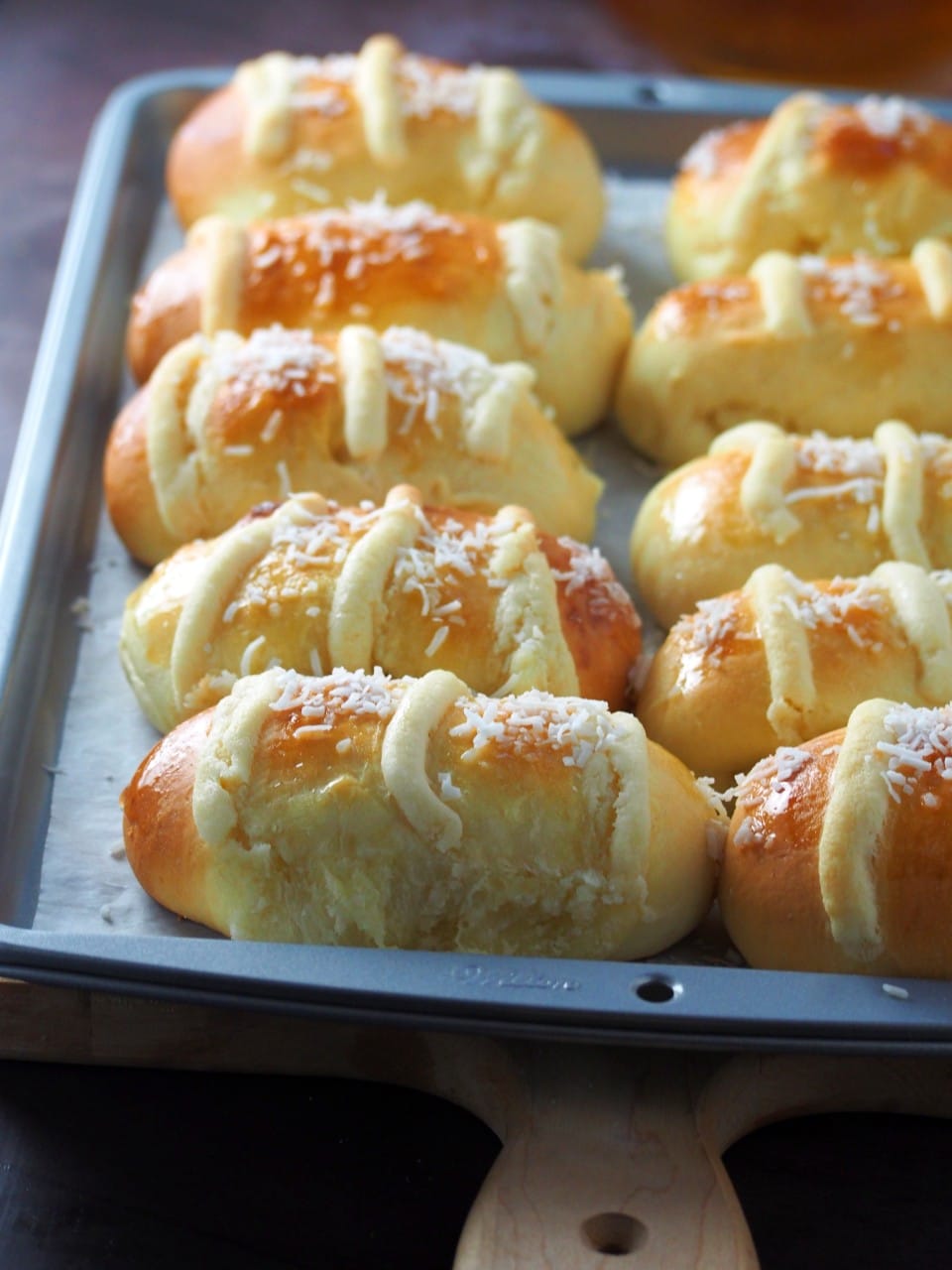 Freshly baked coconut buns on a baking tray.