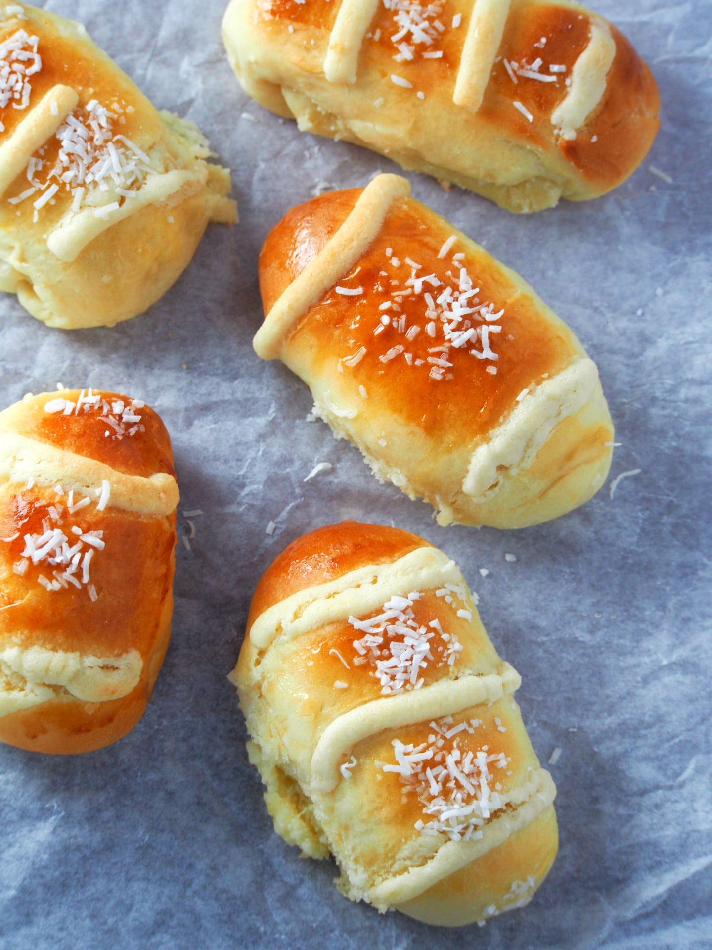 Close up and top view of coconut buns on a parchment paper.