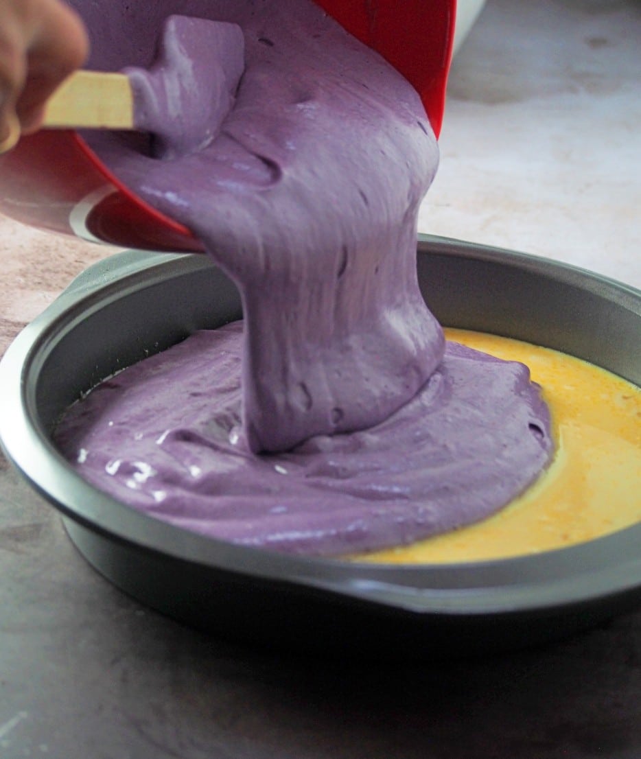 Pouring the ube chiffon cake batter over the custard in the baking pan.