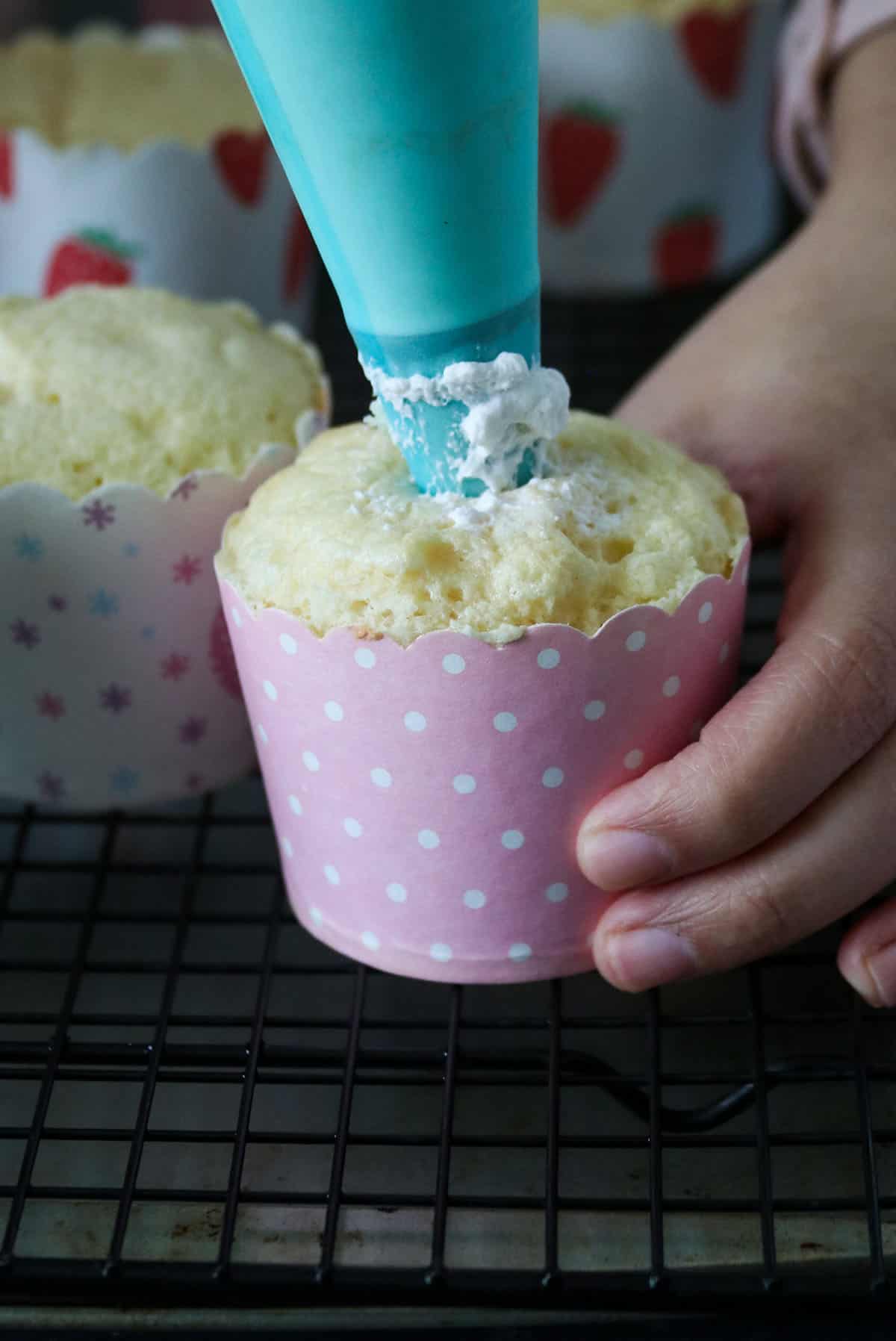 Filling the cupcakes with whipped frosting.