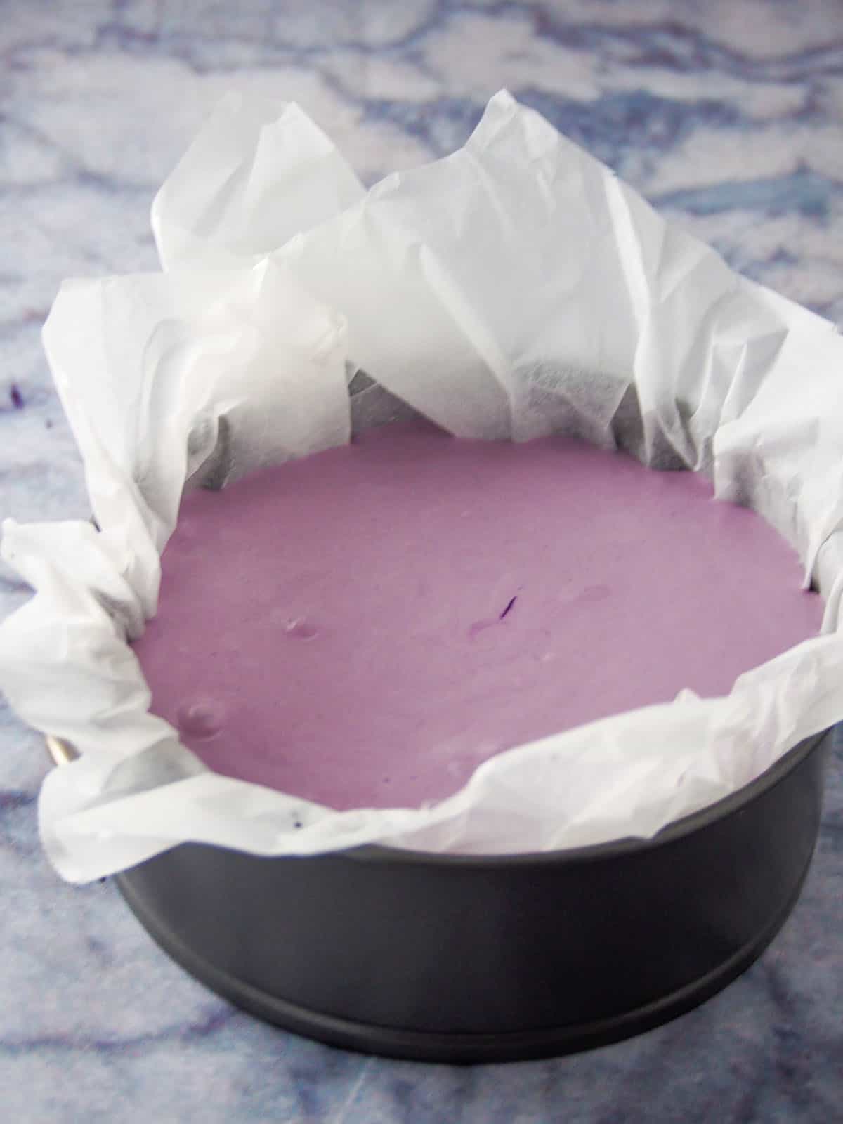 Ube basque cheesecake on a pan, ready for baking.