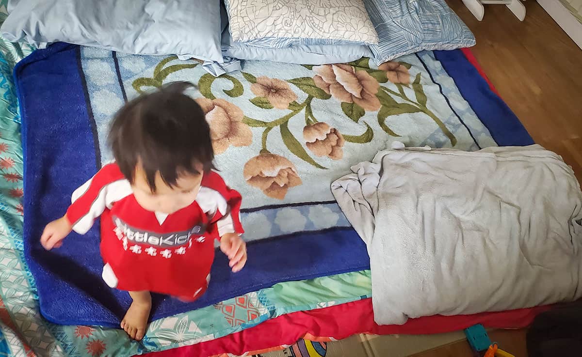 Baby boy walking over blankets. 
