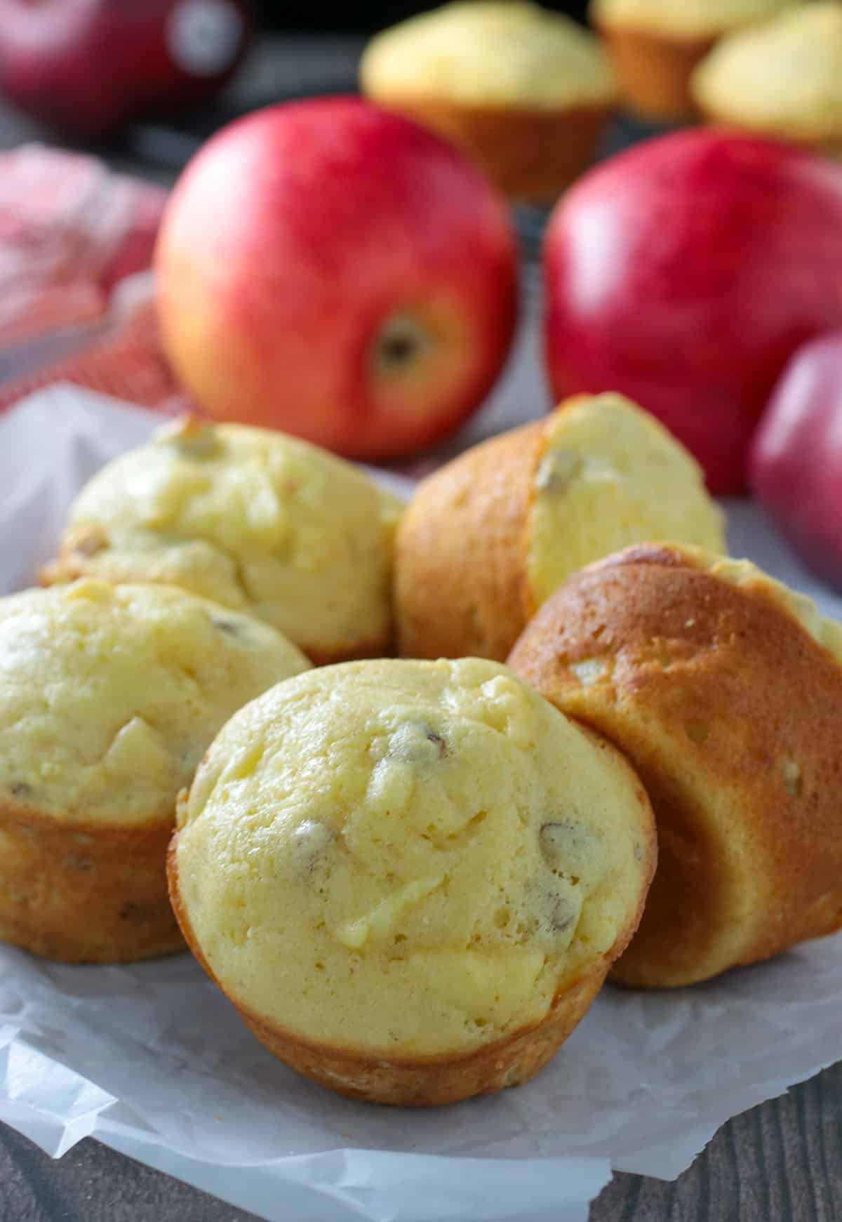 Apple Cornbread Muffins on a table with a background of apples.